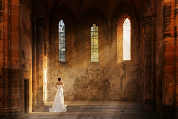 A girl in a white dress in the rays of the sun