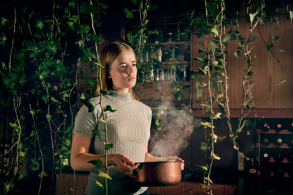 Fille avec une casserole sur les mains sur fond de plantes