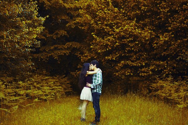 A guy and a girl hug in the autumn forest