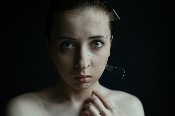 La jeune fille avec des éclats de verre sur le visage