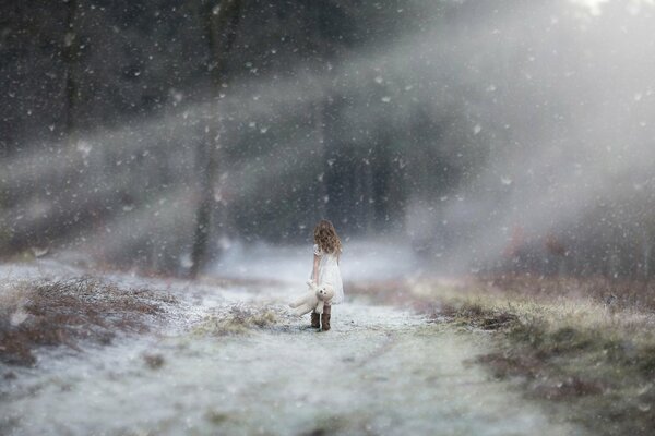 Mädchen im weißen Kleid geht unter dem Schnee