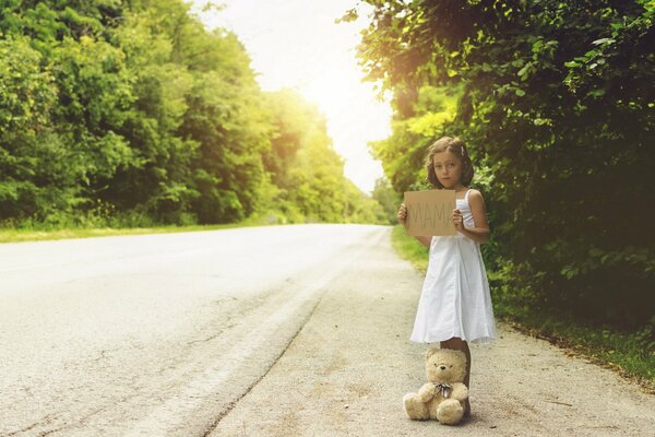 Petite fille avec un ours debout au milieu de la route