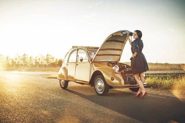 Mädchen auf der Straße schaut unter die Motorhaube eines Citroen 2cv