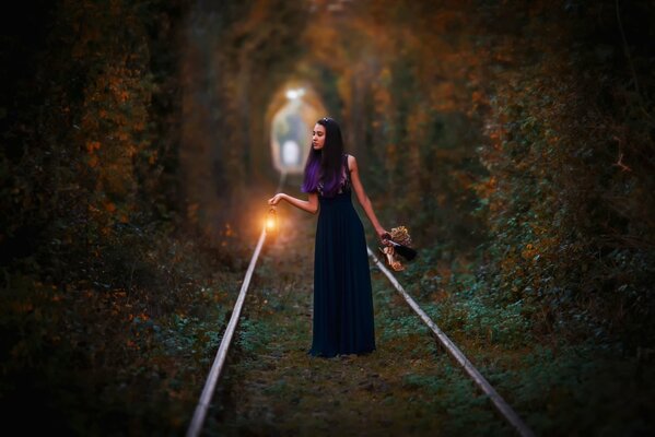 A girl at sunset is walking on the railway