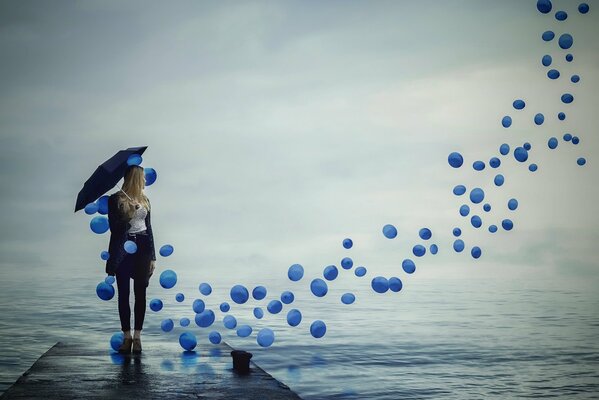 Fille avec un parapluie à la recherche de ballons qui s envolent dans le ciel