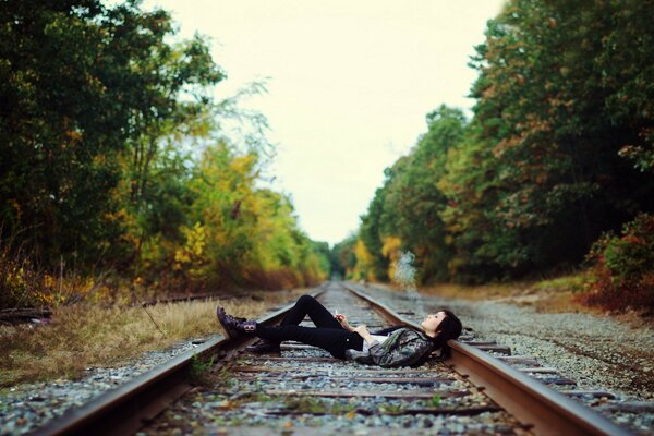 The girl lies and smokes on the rails