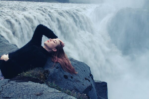 Ragazza in nero si trova sul bordo di una cascata