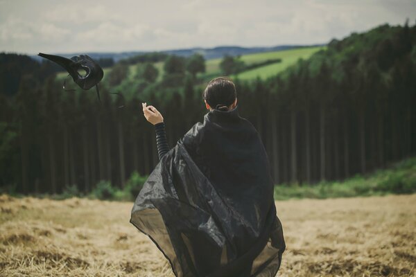 A girl in a black robe drops her mask