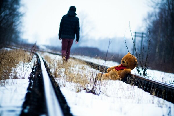 Oso de peluche en los rieles en invierno