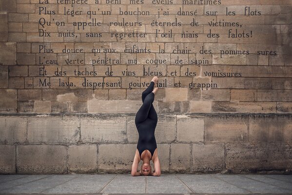 Bailarina en pose contra una pared de fondo con versos