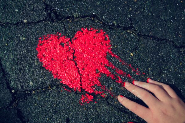 A heart painted in red paint on the asphalt