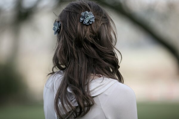 Mädchen von hinten mit langen Haaren und Blumen, die darin verwoben sind