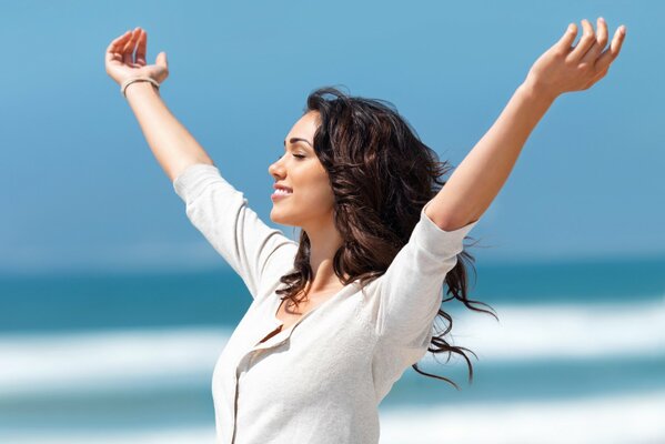 Ragazza sorridente felice sullo sfondo del cielo e del mare