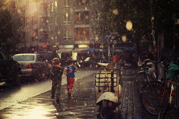 Niños corriendo por la acera bajo la lluvia