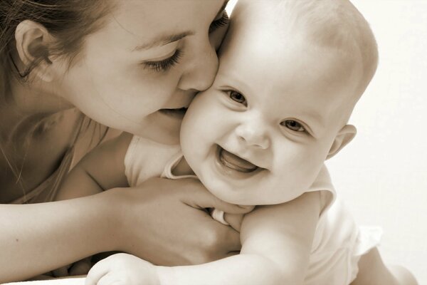 Mom kisses a smiling baby