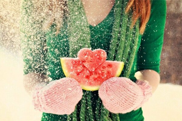 Rothaarige Mädchen im Winter in Fäustlingen hält eine Wassermelone