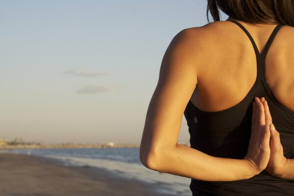 A girl does yoga on the seashore