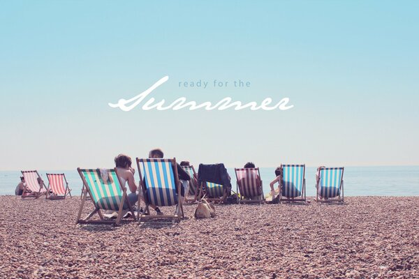 Vacationers in sun loungers on a pebble beach