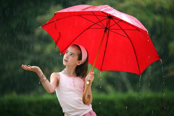 Mädchen mit einem roten Regenschirm bei Regenwetter