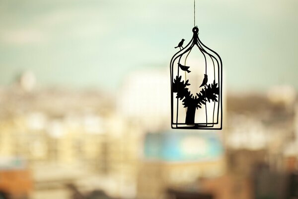 Decoration of a bird in a cage on the background of the city