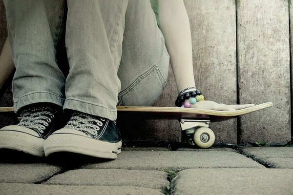 A girl in sneakers is sitting on a skateboard