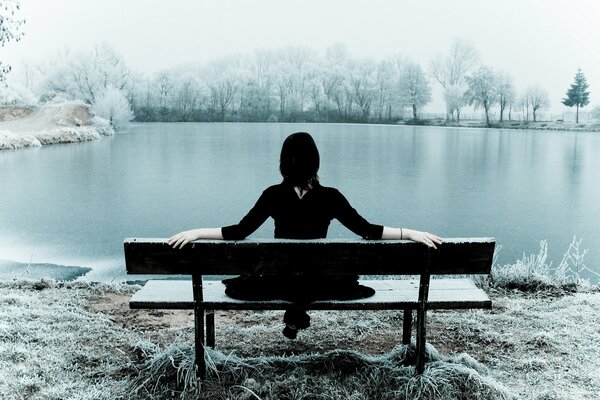 Fille assise sur un banc au bord du lac