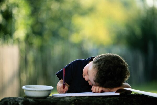 Enfant écrit couché avec un crayon