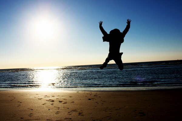 Mann springt am Strand am Meer