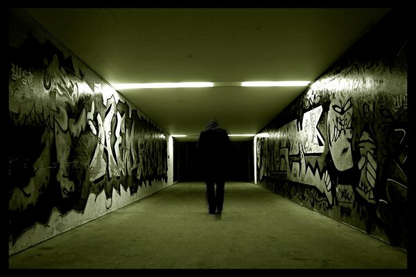 Imagen sombría de un hombre en el metro con graffiti