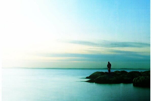 A lonely man stands far away on the seashore