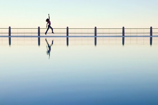 A girl bounces on a bridge in the distance