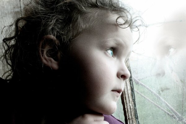 El reflejo de un niño melancólico en una ventana