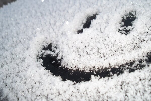 A painted smiley face on a snow-covered glass