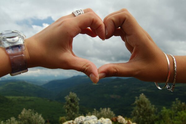 Corazón de las manos en el fondo del hermoso clima