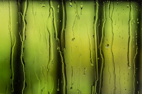 Das Wasser fließt auf dem Glas vor dem Hintergrund grüner Lampen ab