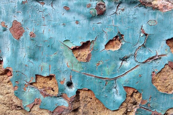 Texture of an old wall with peeling blue plaster