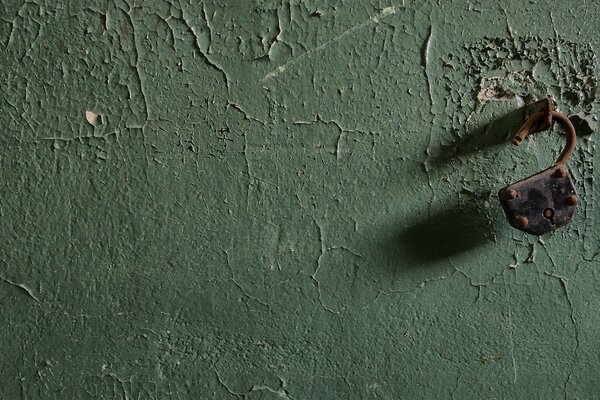 An open lock on an uneven green wall