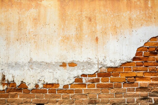 Vieja pared de ladrillo cubierta con yeso nervioso