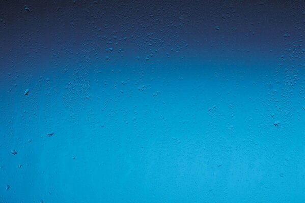 Tropfen auf Glas auf blauem Hintergrund