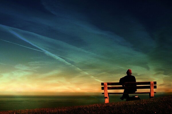 Homme seul sur un banc sur fond de ciel et de mer