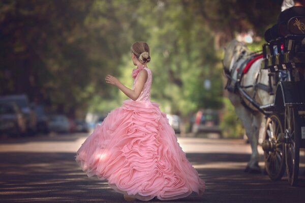 Ragazza in un vestito rosa lussureggiante sulla strada