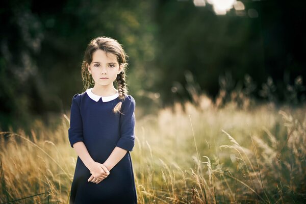 A girl in a dress with pigtails in the field