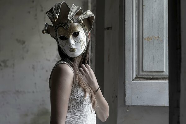 A girl in a stucco mask next to the window