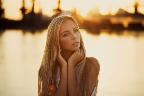 Beautiful girl on the background of water and sunset