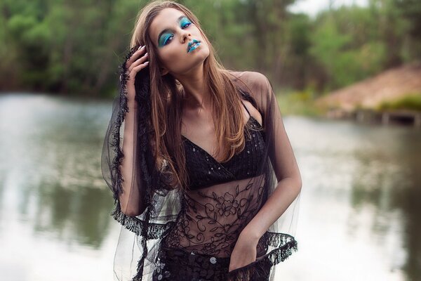 A girl with makeup in summer on the background of a pond