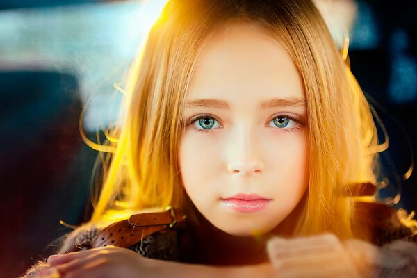 Portrait of a girl with blonde hair in the rays of the sun