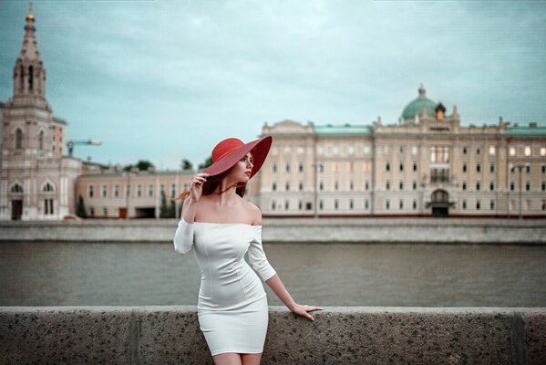 Mädchen in einem weißen Kleid. ein Mädchen mit einem roten Hut. der Fluss. Uferpromenade