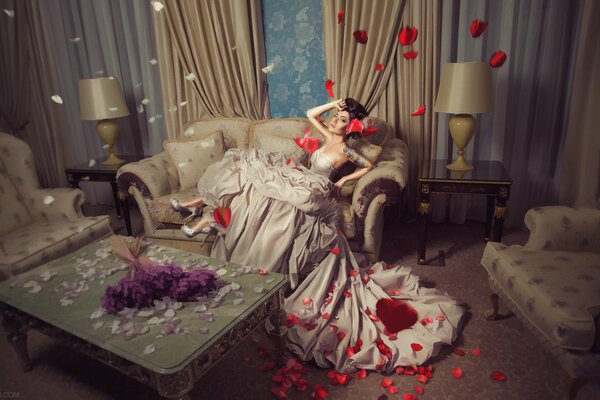 Una chica con un vestido de lujo y pétalos de flores en una habitación de hotel