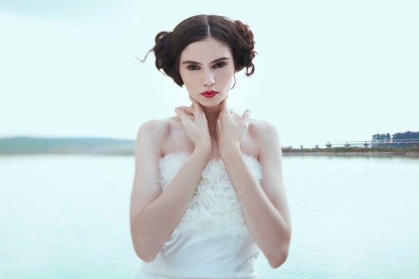 A girl in a white dress on the river bank