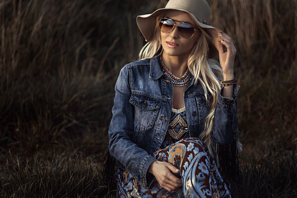 Blonde dans un chapeau et des lunettes sur un fond de meule de foin